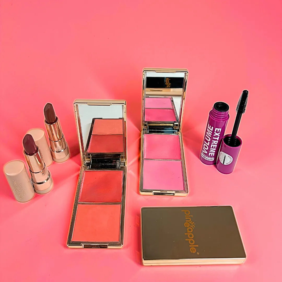 Makeup products including lipsticks, blush, and mascara on a pink background