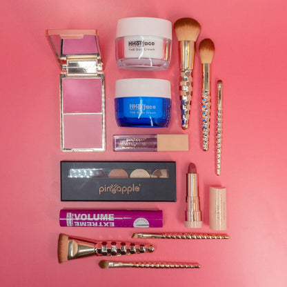 Cosmetic and makeup products laid out on a table with a pink background 